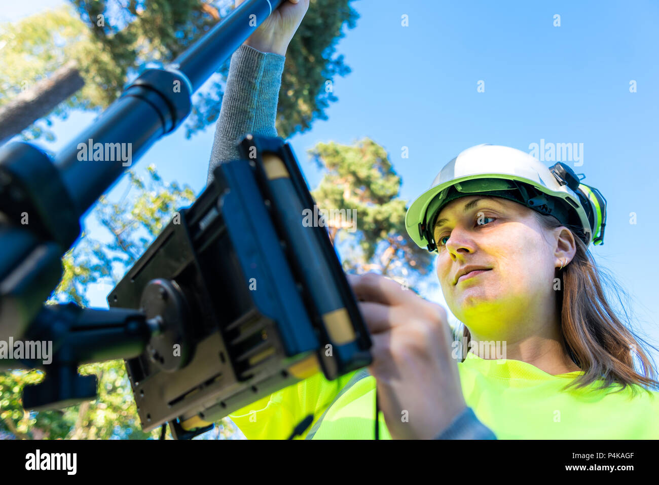 Close up della donna in abiti riflettenti utilizzando il GPS agrimensura utensile con schermo Foto Stock