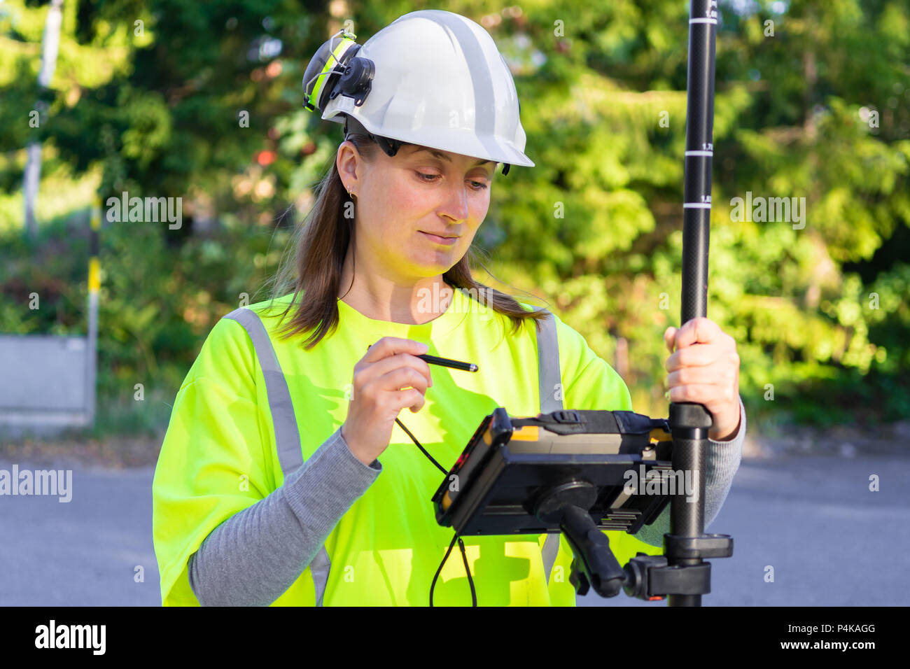 Close up della donna in abiti riflettenti utilizzando il GPS agrimensura utensile con schermo Foto Stock