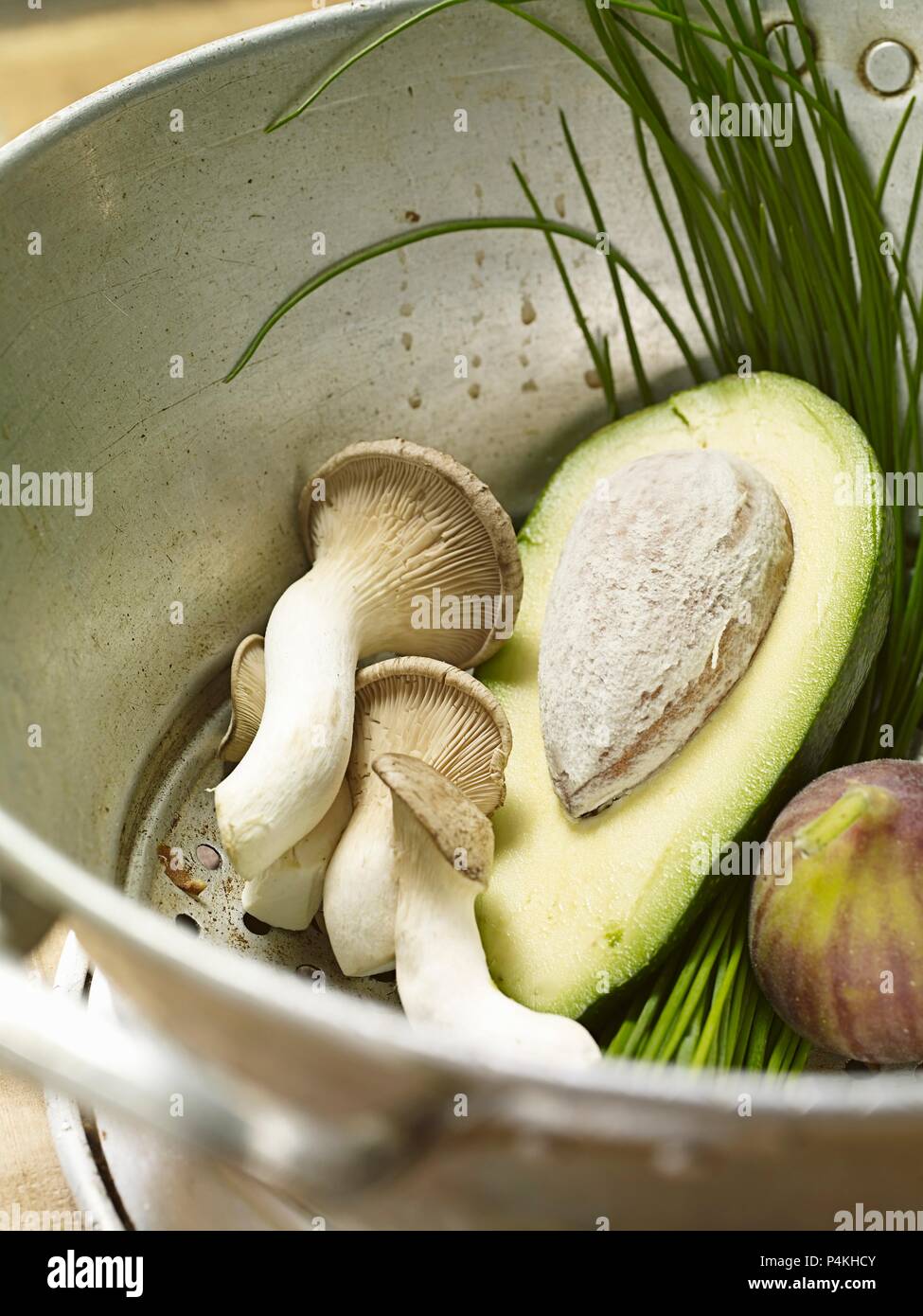 Avocado, funghi, fichi e erba cipollina in uno scolapasta Foto Stock