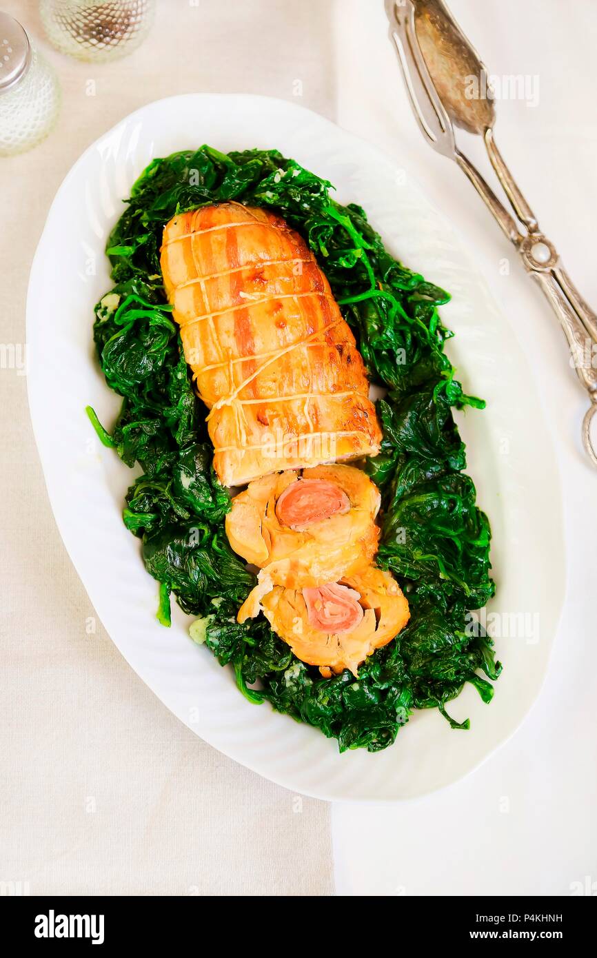 Involtini di pollo con prosciutto e spezie su spinaci saltati Foto Stock