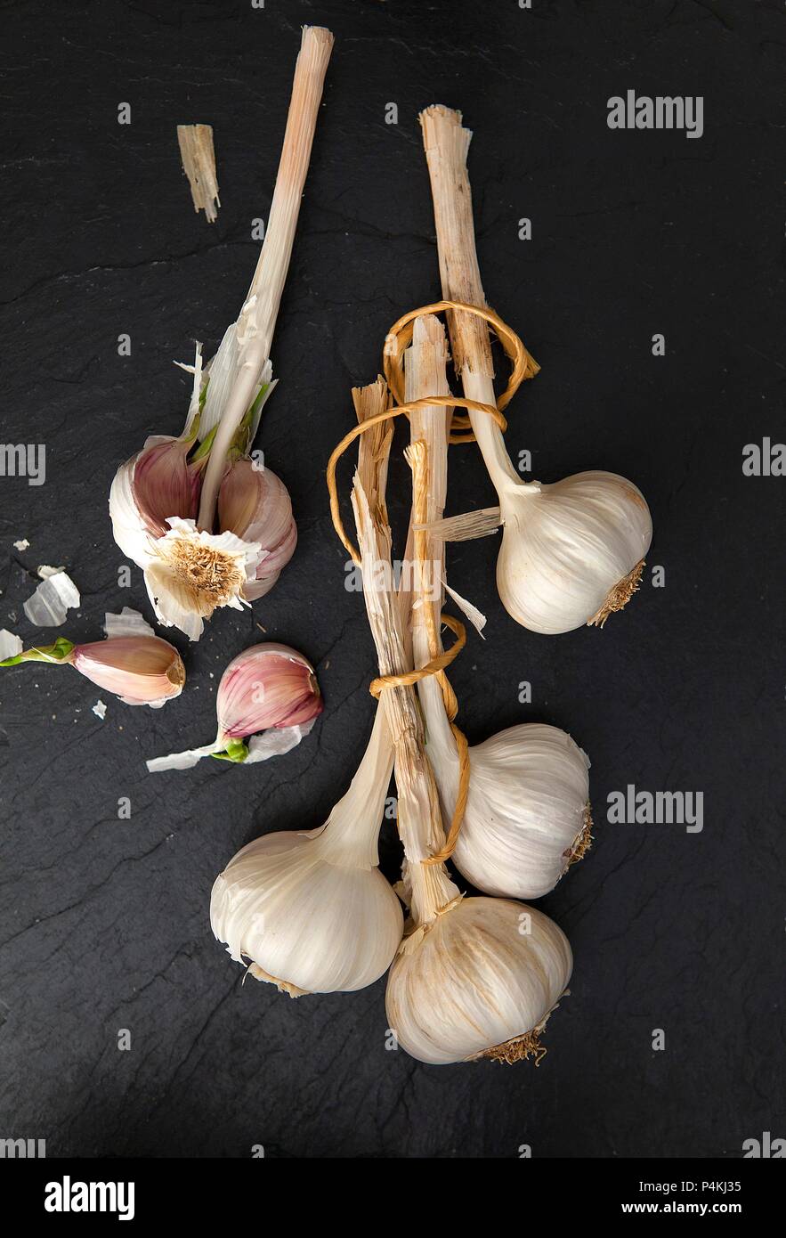 Diversi bulbi di aglio su una superficie di ardesia (visto da sopra) Foto Stock