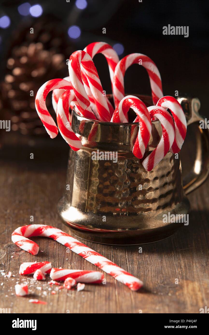 Natale candy cane in uno stile tradizionale oro tazza con uno tutto il possibile sul tavolo per la rottura di una caramella può pezzi Foto Stock