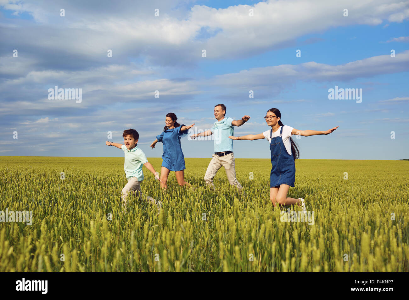 La famiglia felice sorridente in esecuzione sul campo nella natura Foto Stock