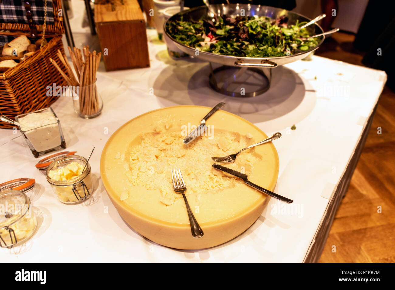 La grande ruota di parmigiano su un contatore del ristorante self service table con coltello e forchetta Foto Stock