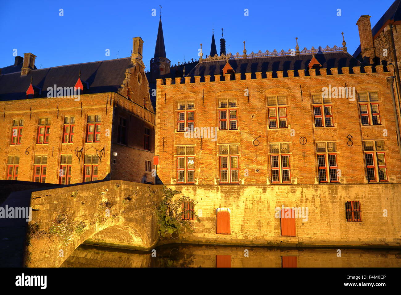 Vista degli edifici del patrimonio di notte riflettendo lungo il canale verde in Bruges, Belgio Foto Stock