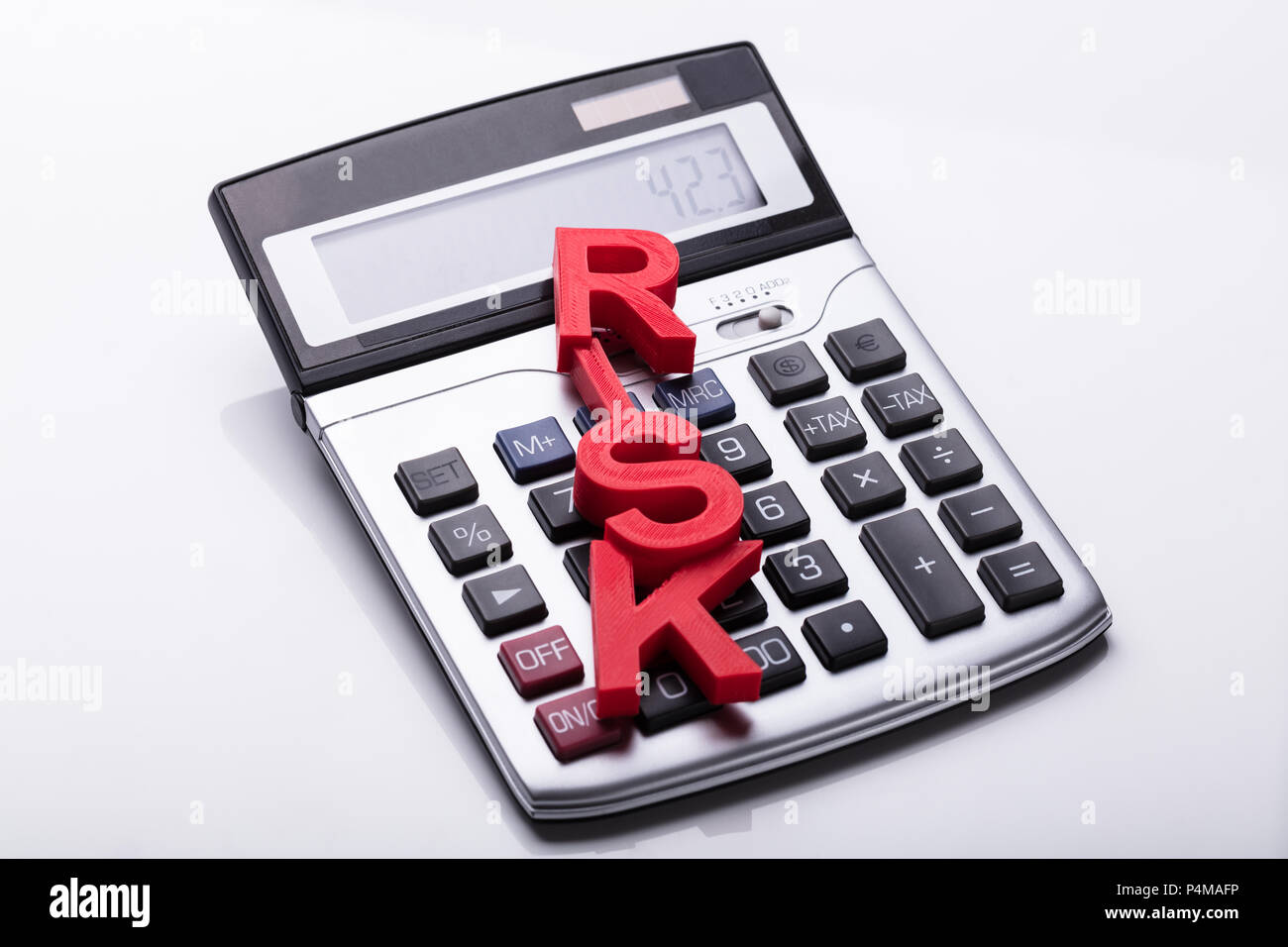 Vista in elevazione della parola rischio sulla calcolatrice su sfondo bianco Foto Stock