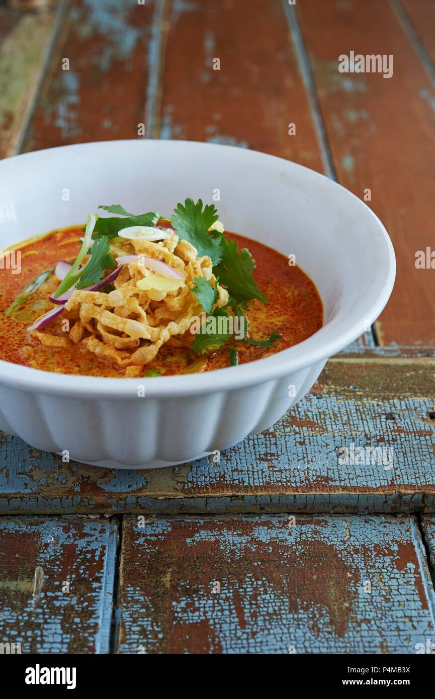 Thai Khao Soi zuppa di noodle. realizzata con i noodle all'uovo, il latte di cocco, giallo curry, il coriandolo, il rosso e il verde di cipolla, e croccante frittura di tagliatelle. Foto Stock