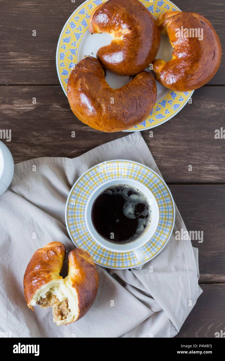 A forma di mezzaluna pasticcini in legno di noce e una tazza di caffè Foto Stock