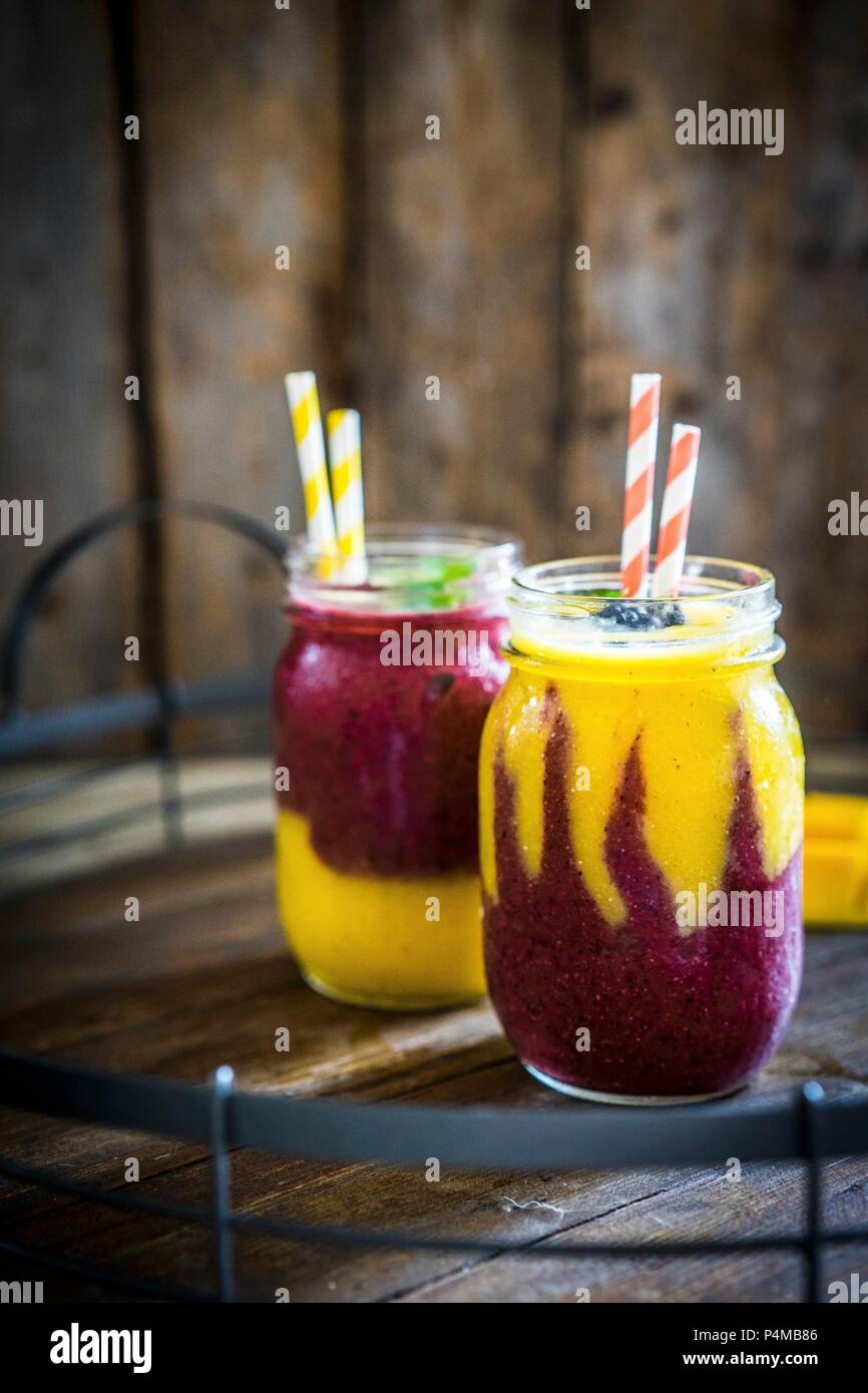 Colorato due layer di mango e berry smoothie guarnita con more Foto Stock