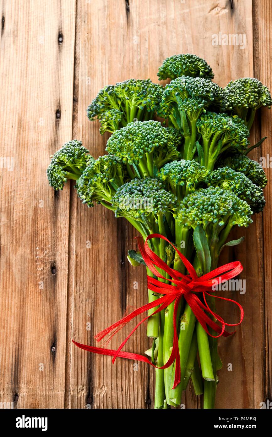 Broccolini con un nastro rosso su una superficie in legno Foto Stock