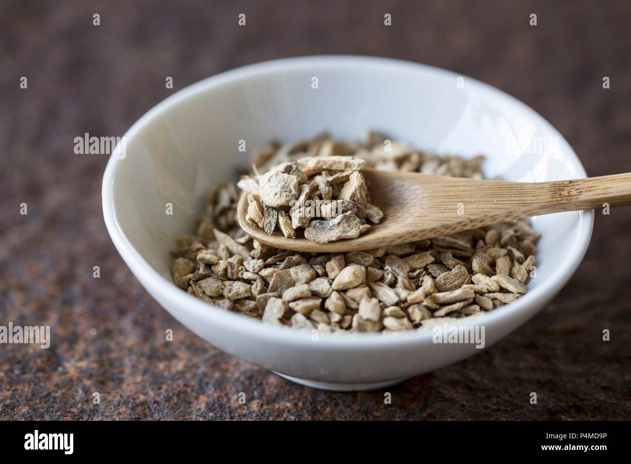 Lo zenzero essiccato con un cucchiaio di legno in una ciotola Foto Stock