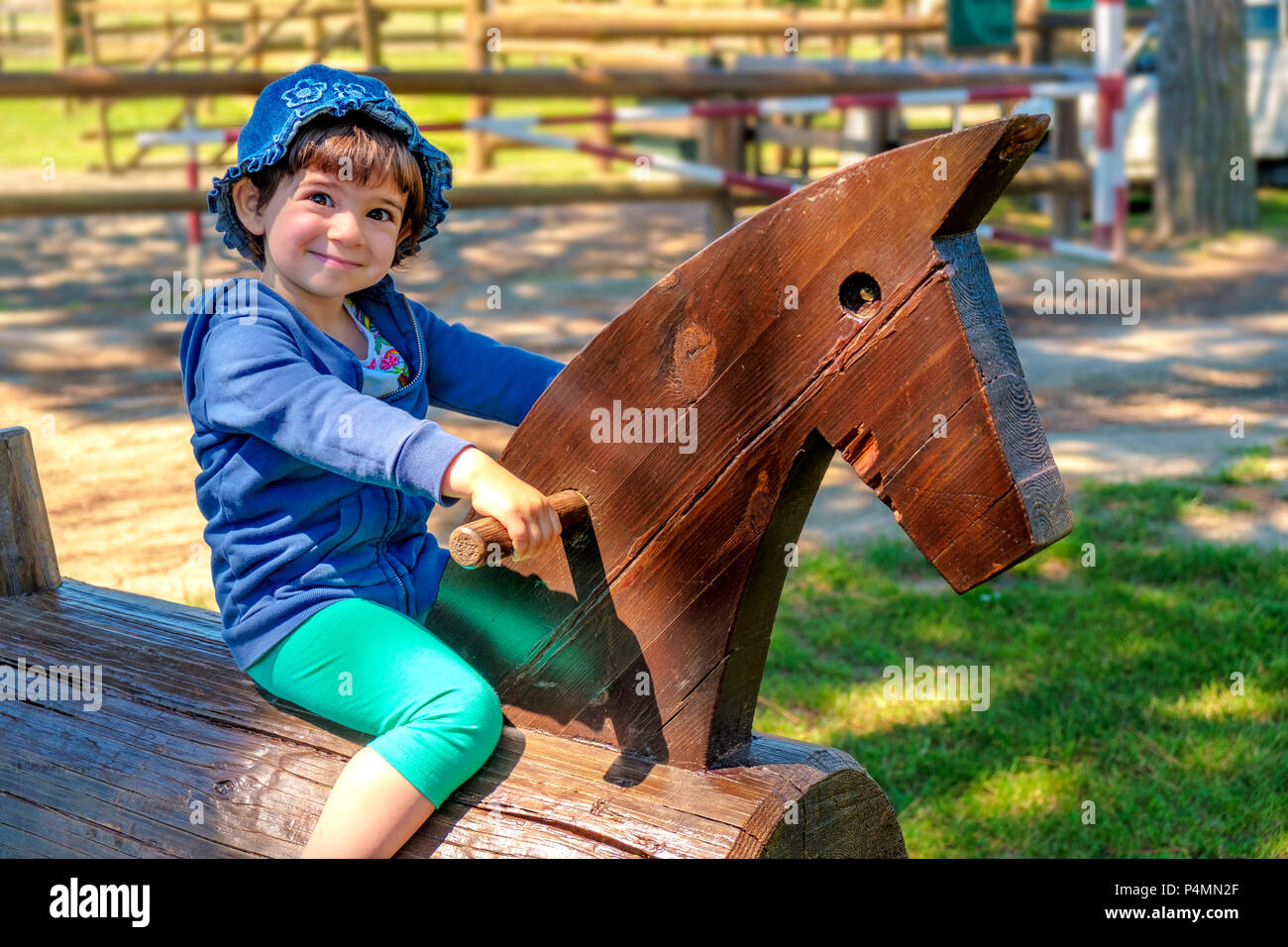 Baby bambino sul cavallo di legno in un ranch - imparare a cavalcare - viaggio con tutta la famiglia a scuola di equitazione maneggio . Foto Stock