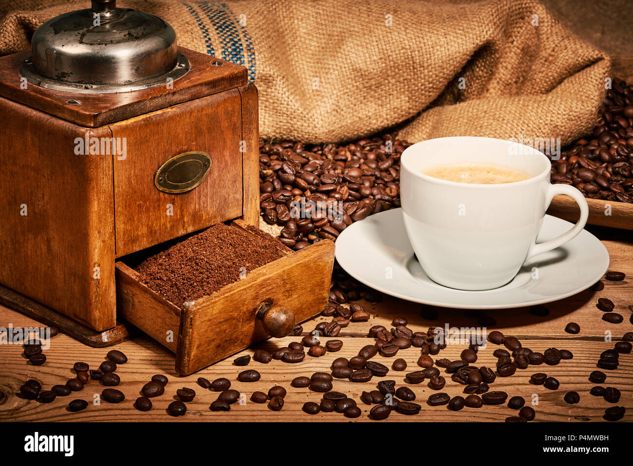 Tazza di caffè con il vecchio macinino da caffè e fagioli sul tavolo di legno Foto Stock