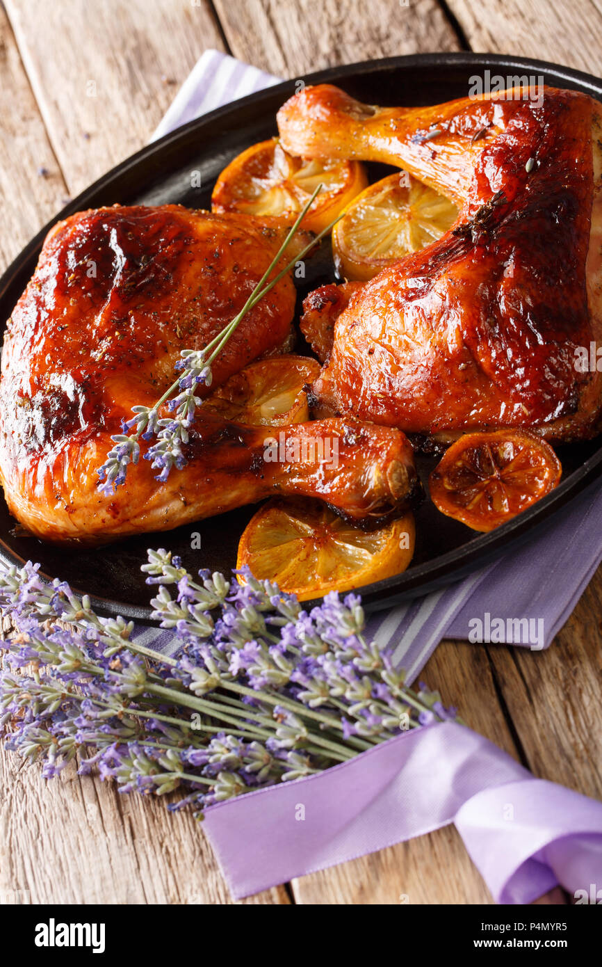 Cibo francese: cotte le cosce di pollo con miele di lavanda e limone close-up su una piastra sul piano verticale. Foto Stock