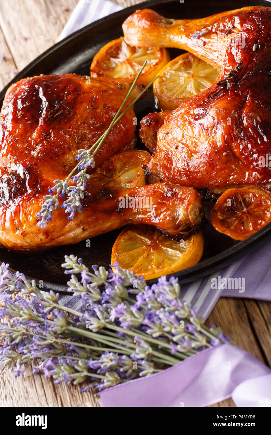 Cotte le cosce di pollo con miele di lavanda e limone close-up su una piastra su un piano verticale. Foto Stock