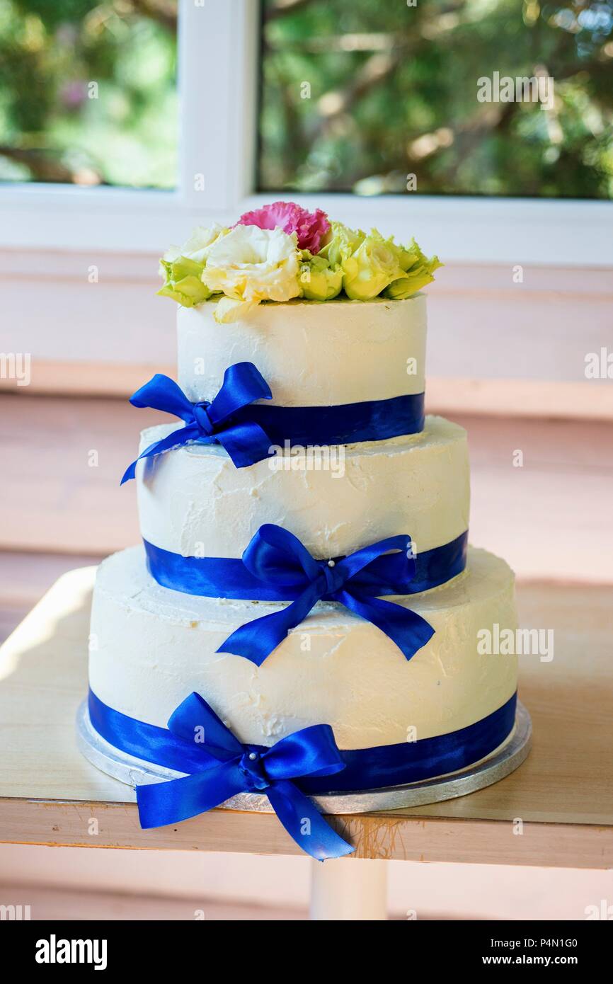 Una tre-tiered crema di burro torta di nozze con blu di nastri di seta Foto Stock