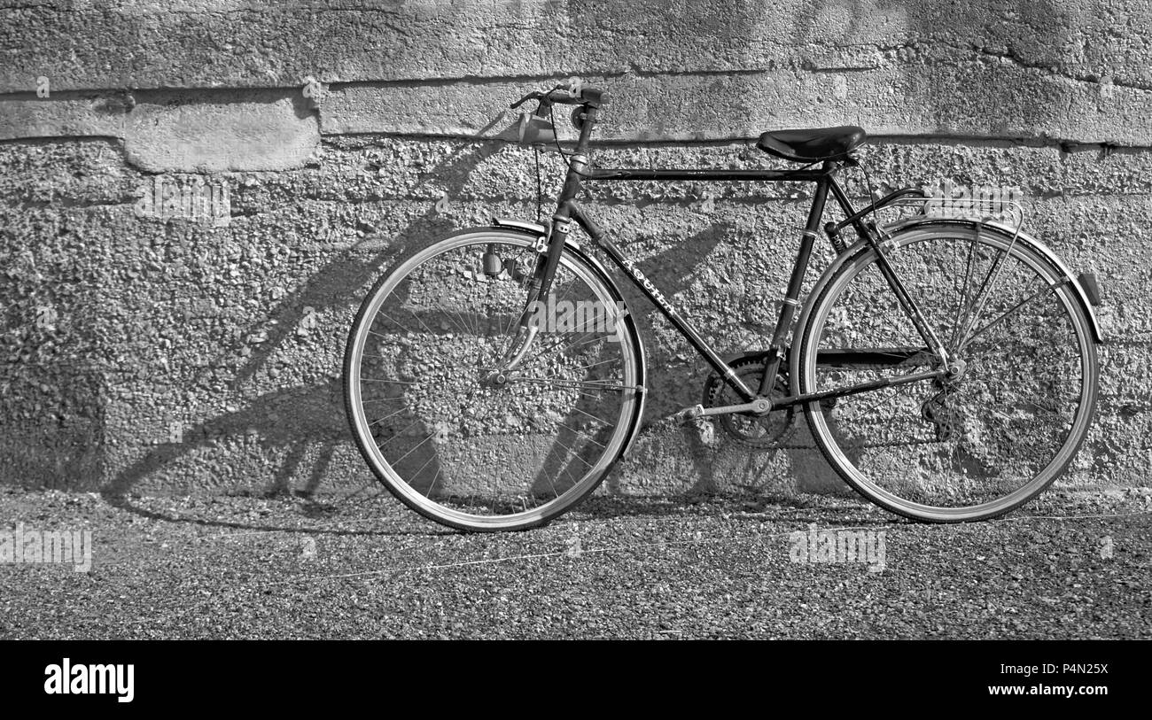 Una vecchia bicicletta appoggiata al muro Foto Stock