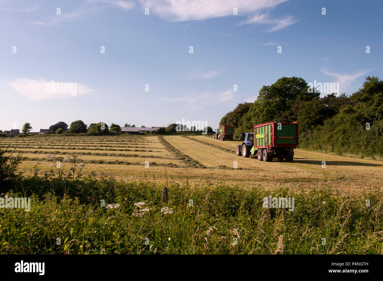 Due trattori la raccolta di fieno in un campo vicino a Sturminster Newton Dorset, Regno Unito Foto Stock