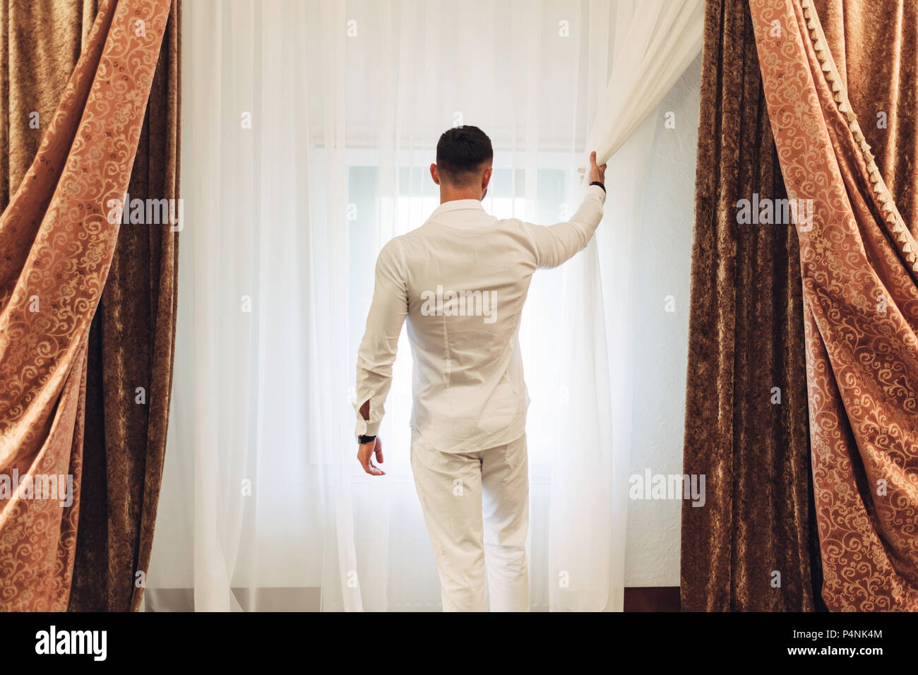 Giovane uomo in abito bianco in camera di albergo Foto Stock