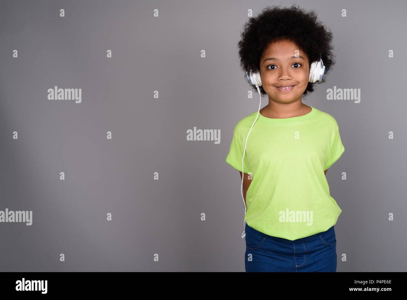 Giovane carina ragazza africana ascoltando musica contro backgrou grigio Foto Stock