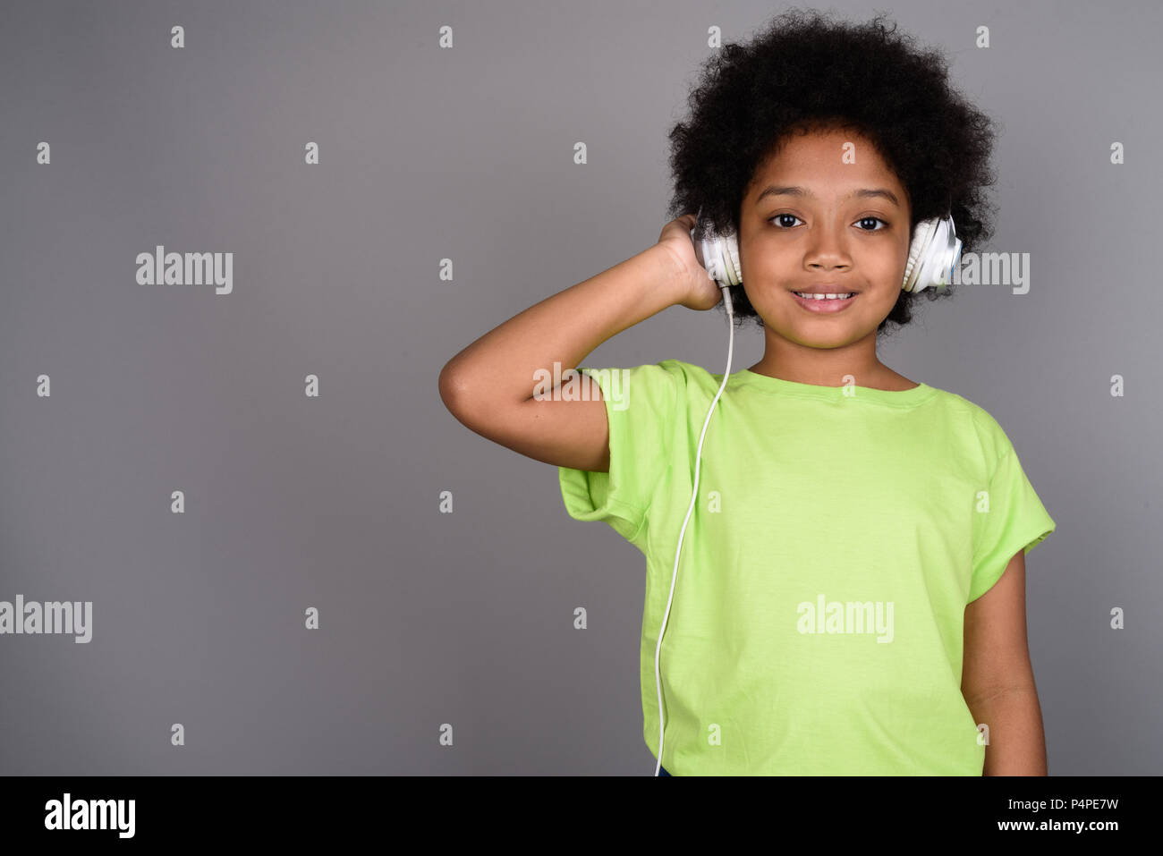 Giovane carina ragazza africana ascoltando musica contro backgrou grigio Foto Stock