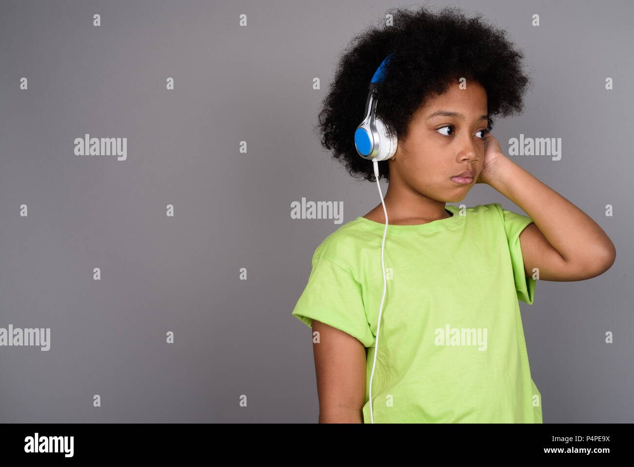 Giovane carina ragazza africana ascoltando musica contro backgrou grigio Foto Stock