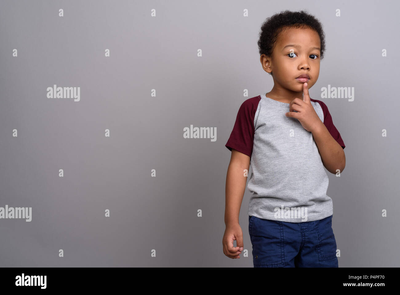 Giovani carino ragazzo africano contro uno sfondo grigio Foto Stock