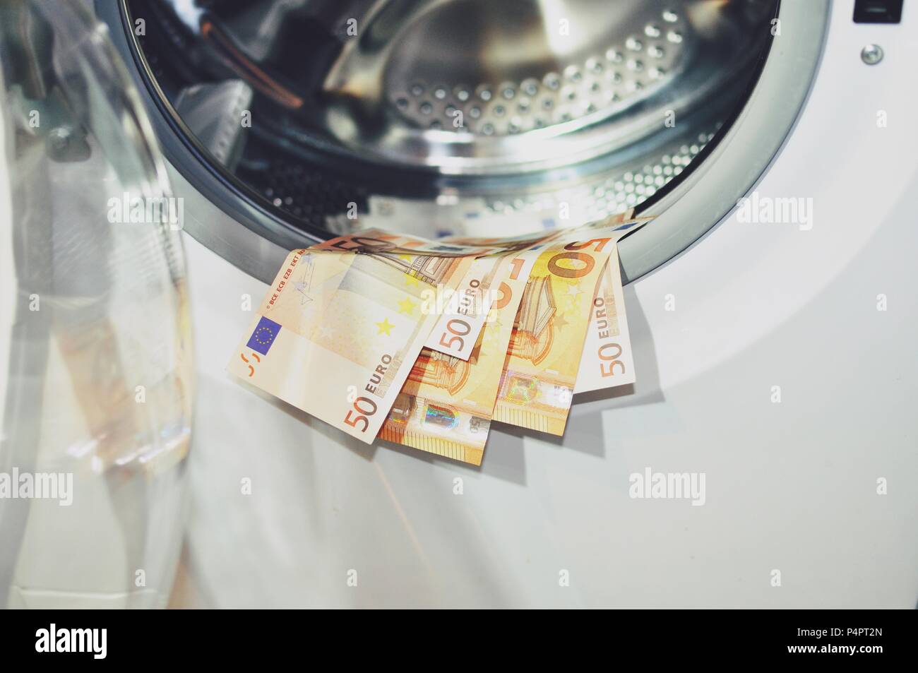 Il denaro messo ad asciugare sul bordo della macchina di lavaggio con la porta aperta, vicino. Il riciclaggio di denaro il simbolo Foto Stock