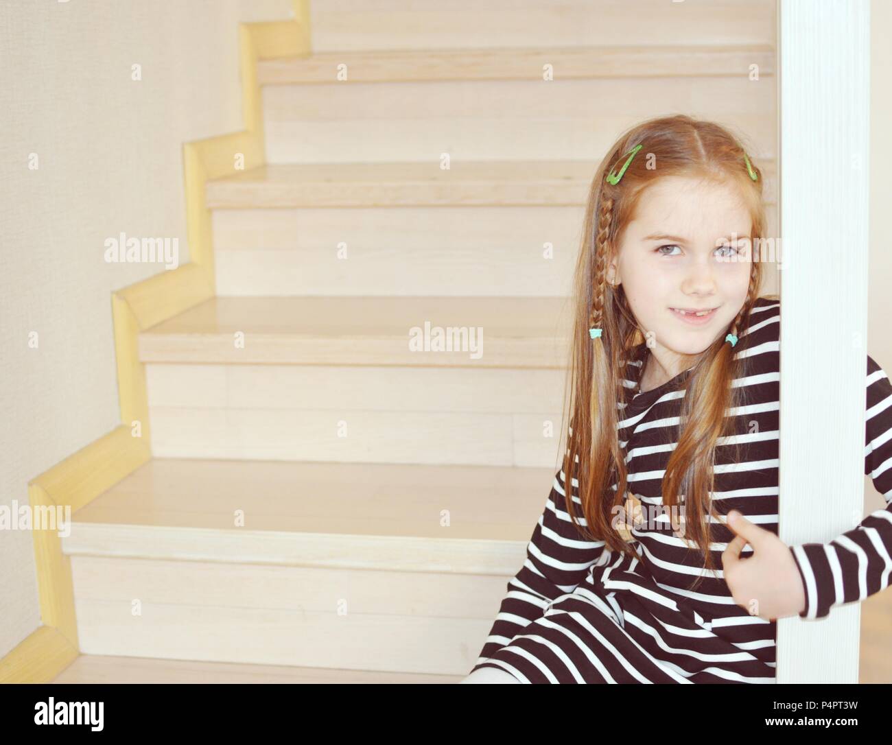 Bambino biondo, ragazza 7-9 anni, stando in piedi sui gradini e sorridente, closeup ritratto, spazio copia Foto Stock
