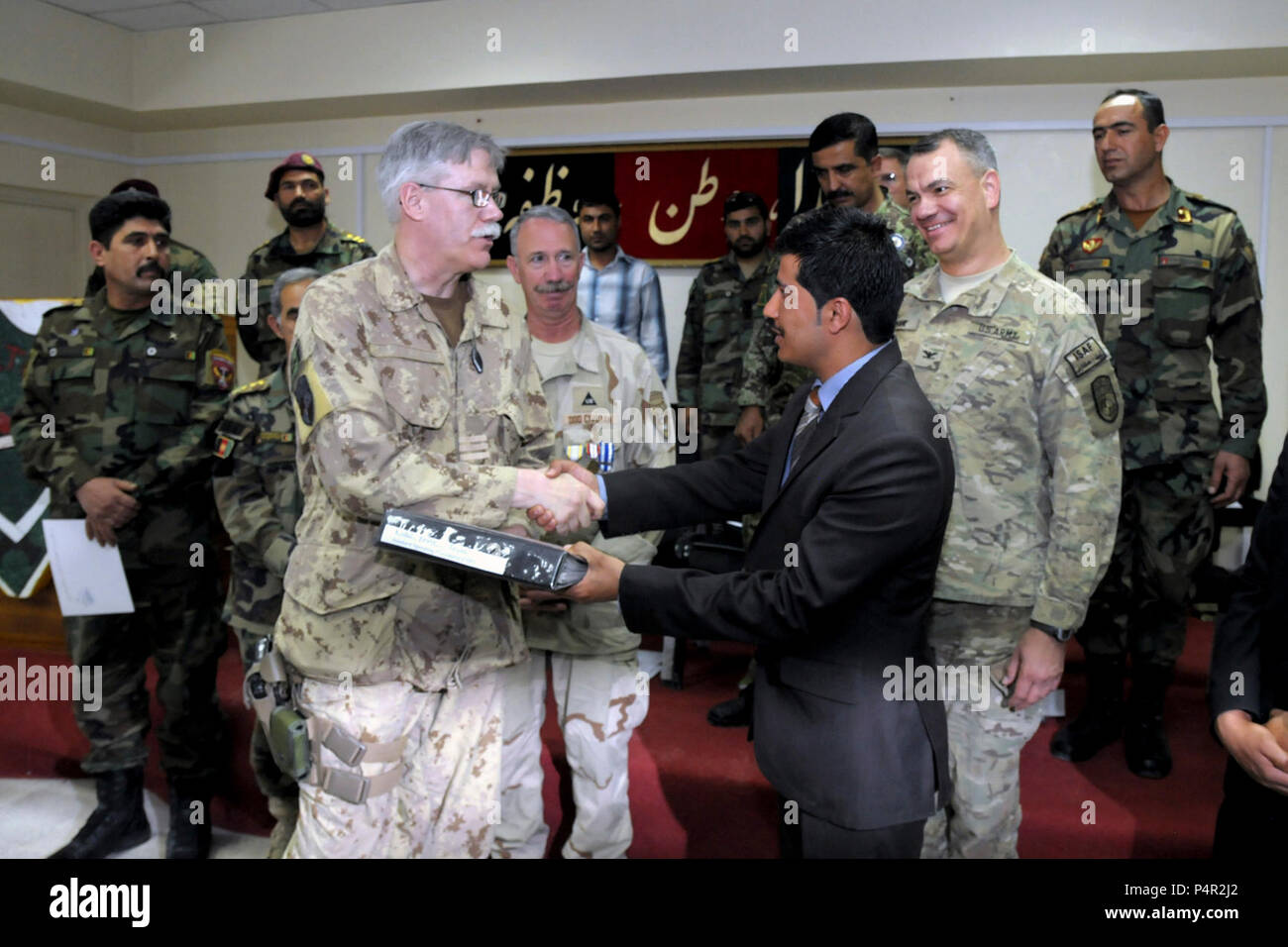 KABUL, Afghanistan (16 maggio 2012) -- come un gesto simbolico di transizione dal Comando americano di amministrazione afghana di Morehead English Language Training Center (MELTC) all interno della scuola di eccellenza, il "Libro di procedure operative" è passato dalla Canadian Lt. Col. Jean-Guy Levesque al sig. Emal Salarzai, dal Awista Knowledge Village Company, il nuovo sito di piombo e supervisore della Scuola di inglese su Camp Morehead, in una cerimonia che si terrà il 16 maggio 2012. Foto Stock