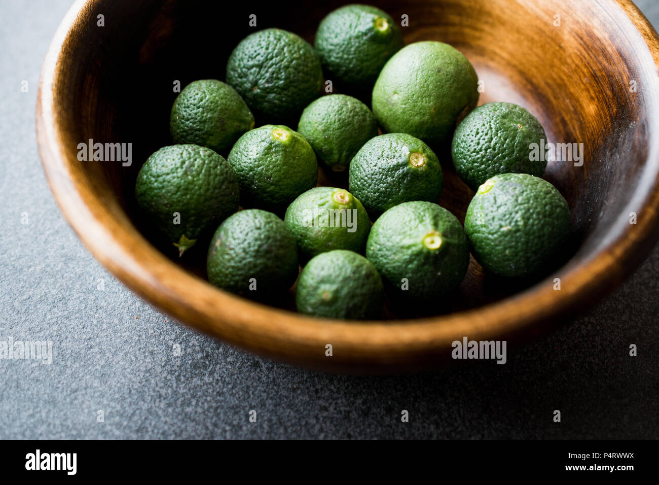 Immaturo immaturo Verde biologico Limes nella ciotola di legno. Alimenti biologici. Foto Stock