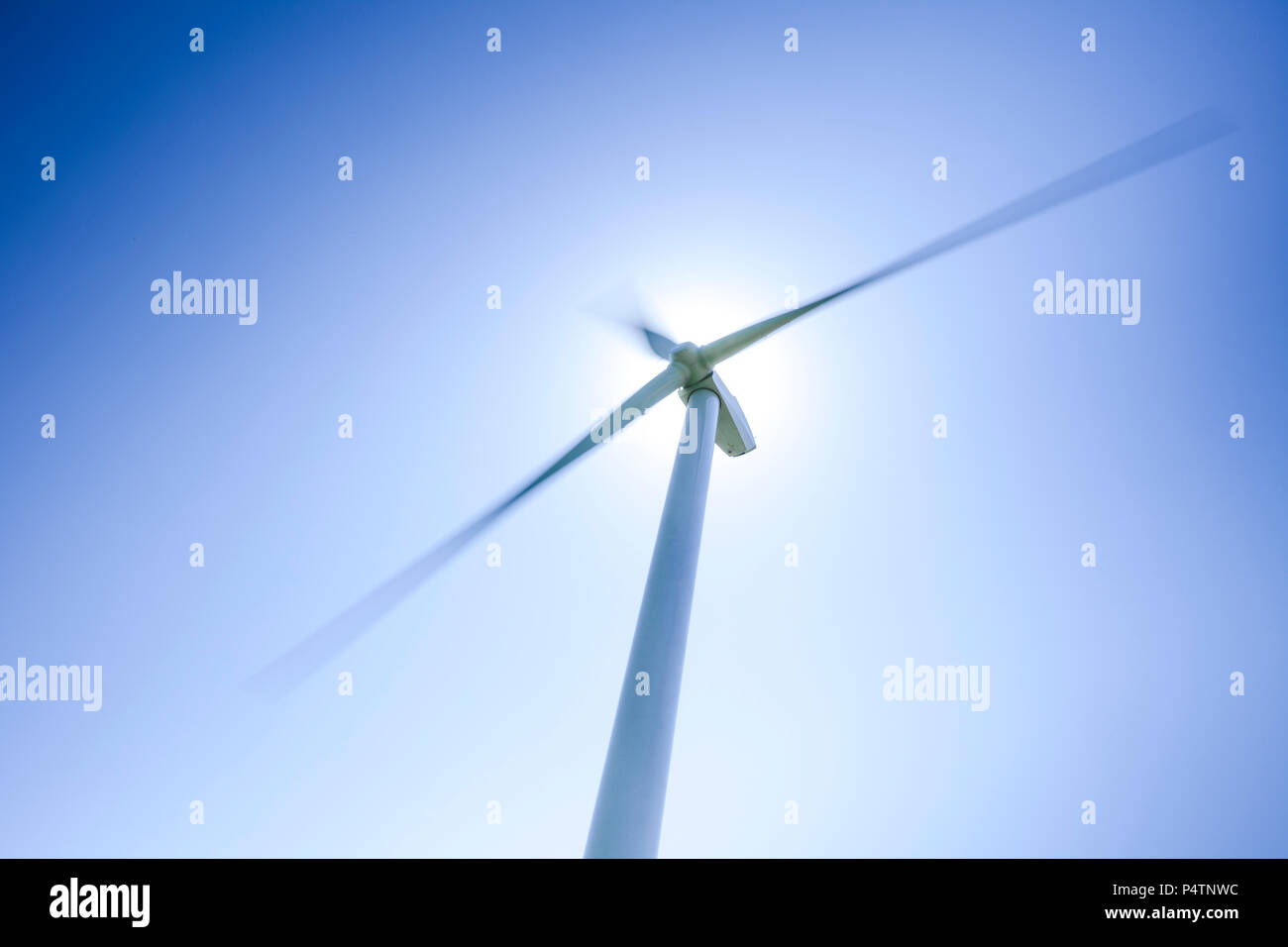 Vento turbinein azione in un parco di mulini a vento contro un cielo blu chiaro. Foto Stock