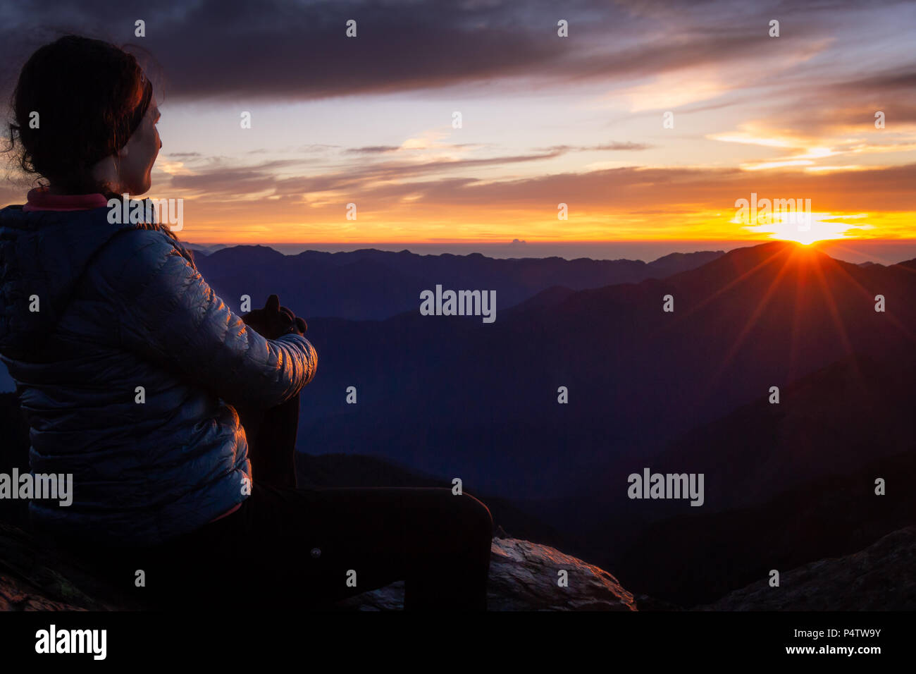 Donna ammirando Alba sulla cima di una montagna Foto Stock