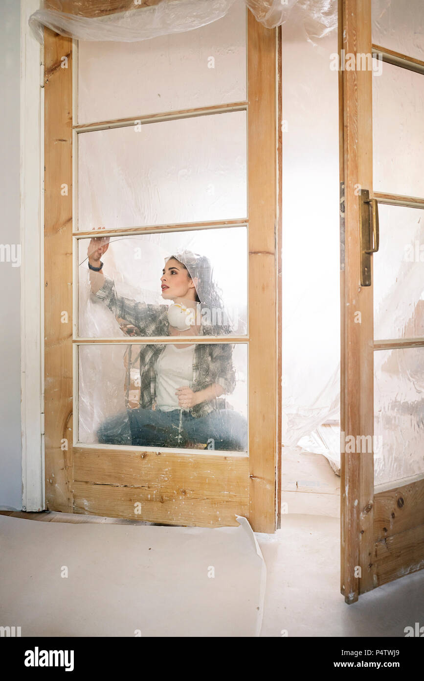 Giovane donna rinnovando il suo nuovo appartamento, esaminando la porta Foto Stock