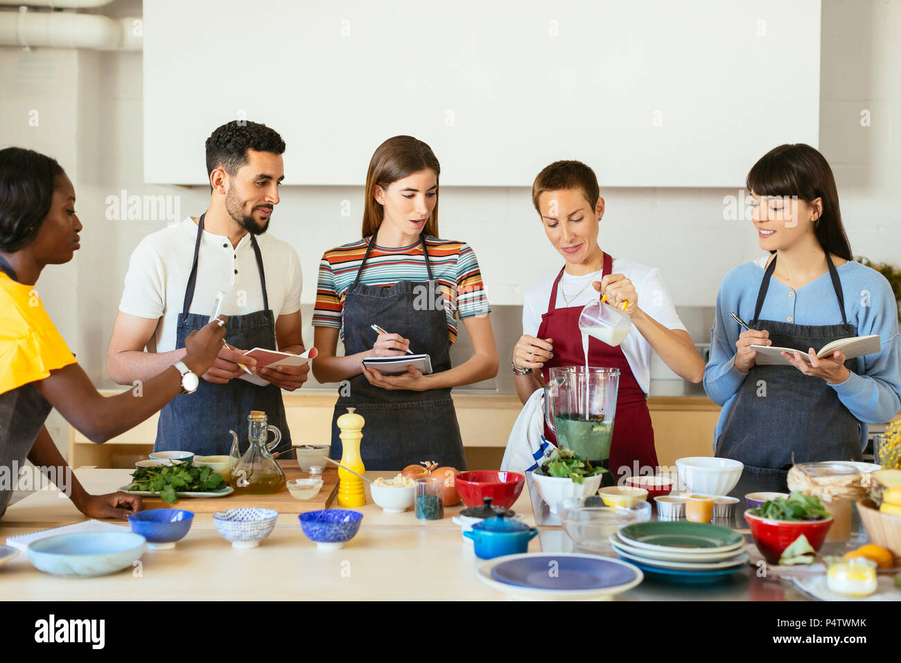 Amici e istruttore in un workshop di cottura preparare un smoothie Foto Stock