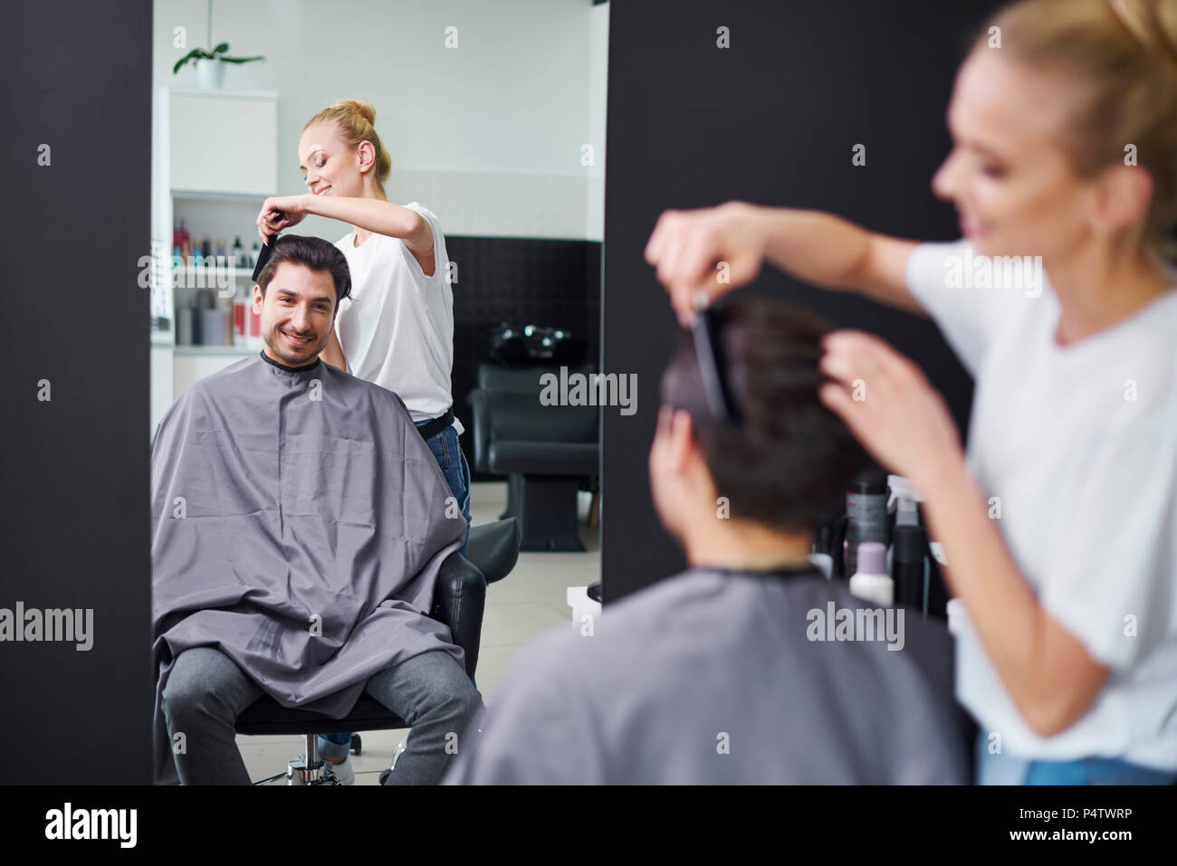 Sorridente parrucchiere uomo di pettinatura dei capelli Foto Stock