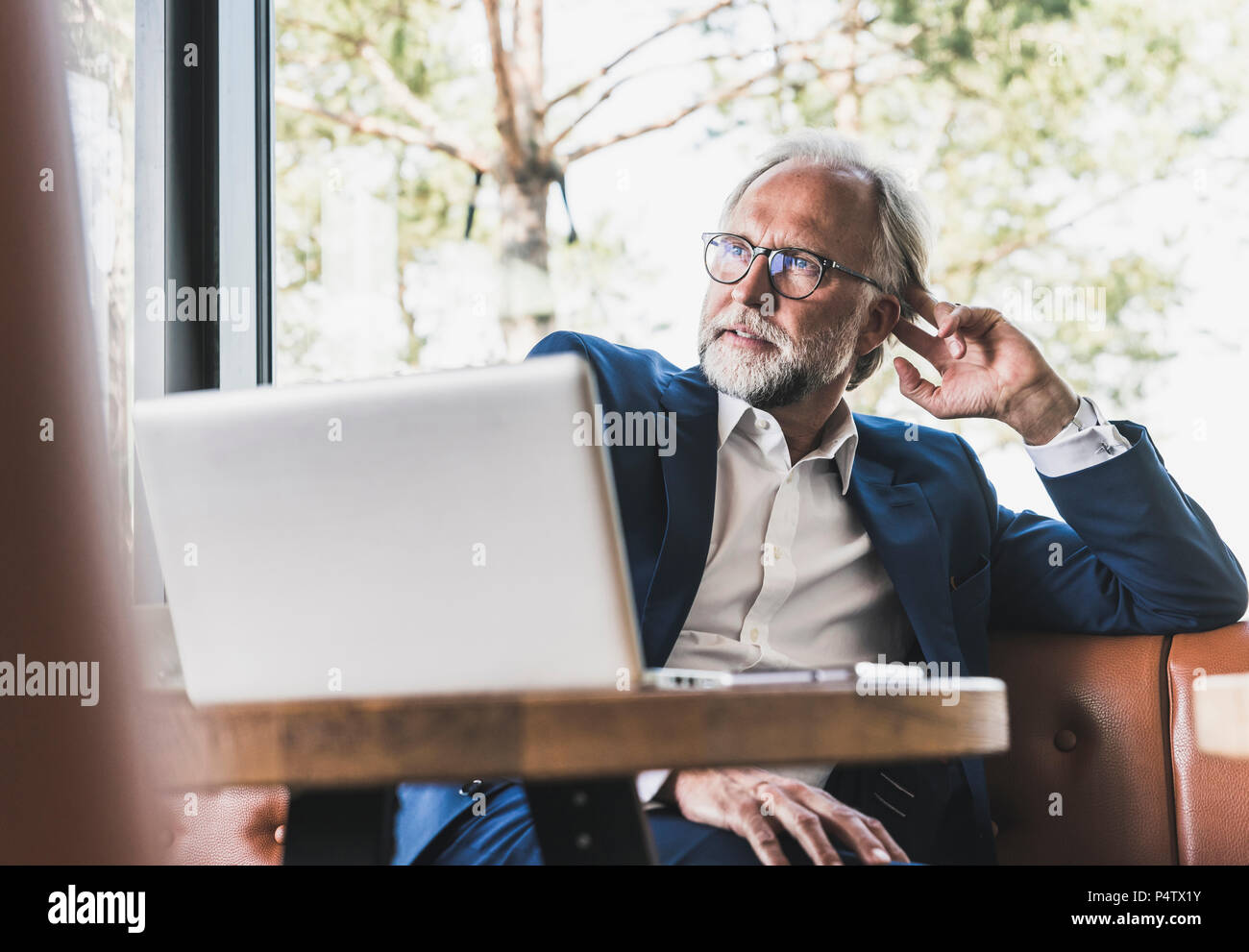 Imprenditore maturo seduta a tavola in un cafe con il computer portatile Foto Stock