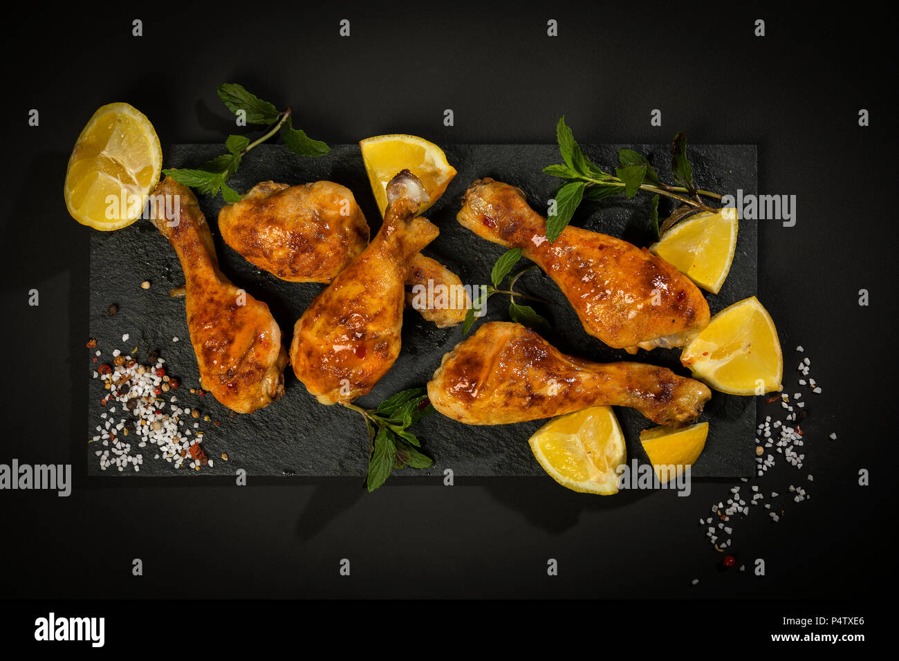 Il pollo al forno le gambe sull'ardesia, limone Foto Stock
