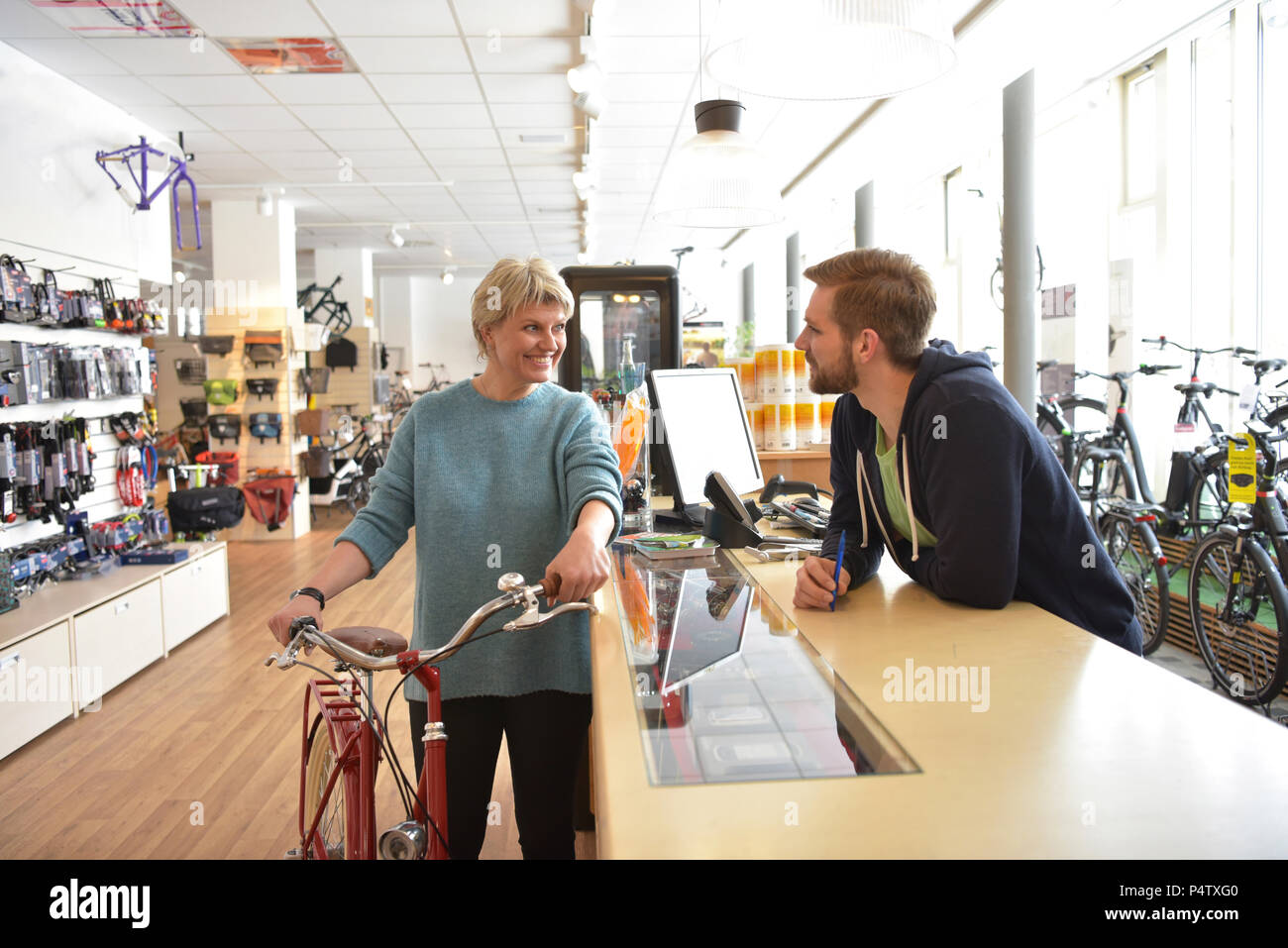 Addetto alle vendite ad aiutare il cliente nel negozio di biciclette Foto Stock