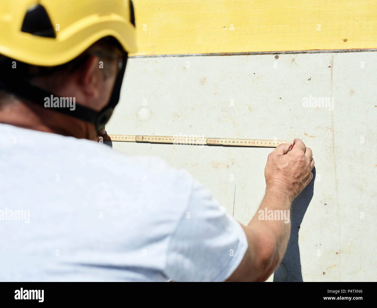 Lavoratore edile con righello e matita su muro di cemento Foto Stock