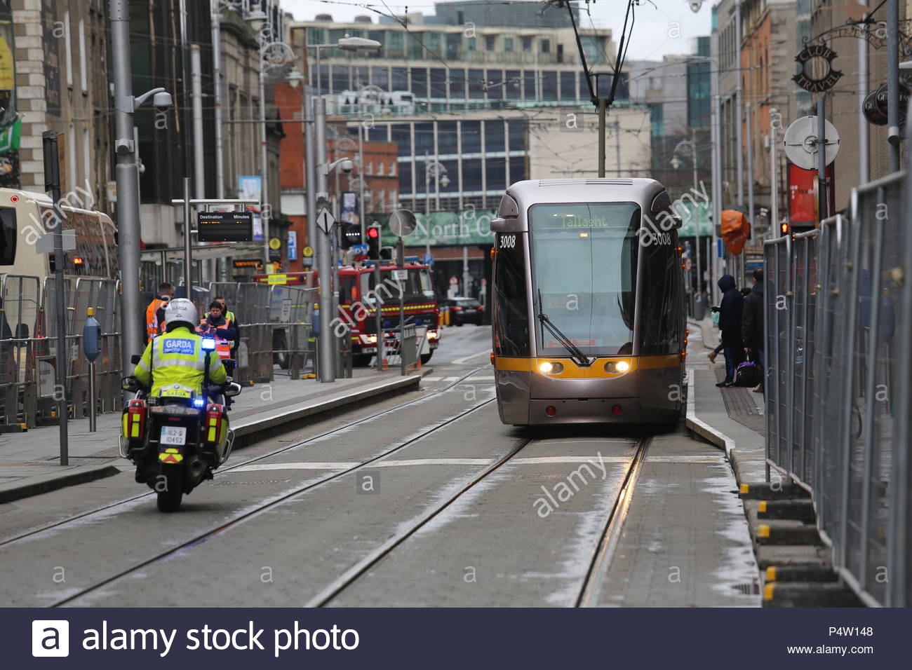 Garda su una motocicletta in prossimità di un treno Luas nel centro della città di Dublino, Irlanda Foto Stock