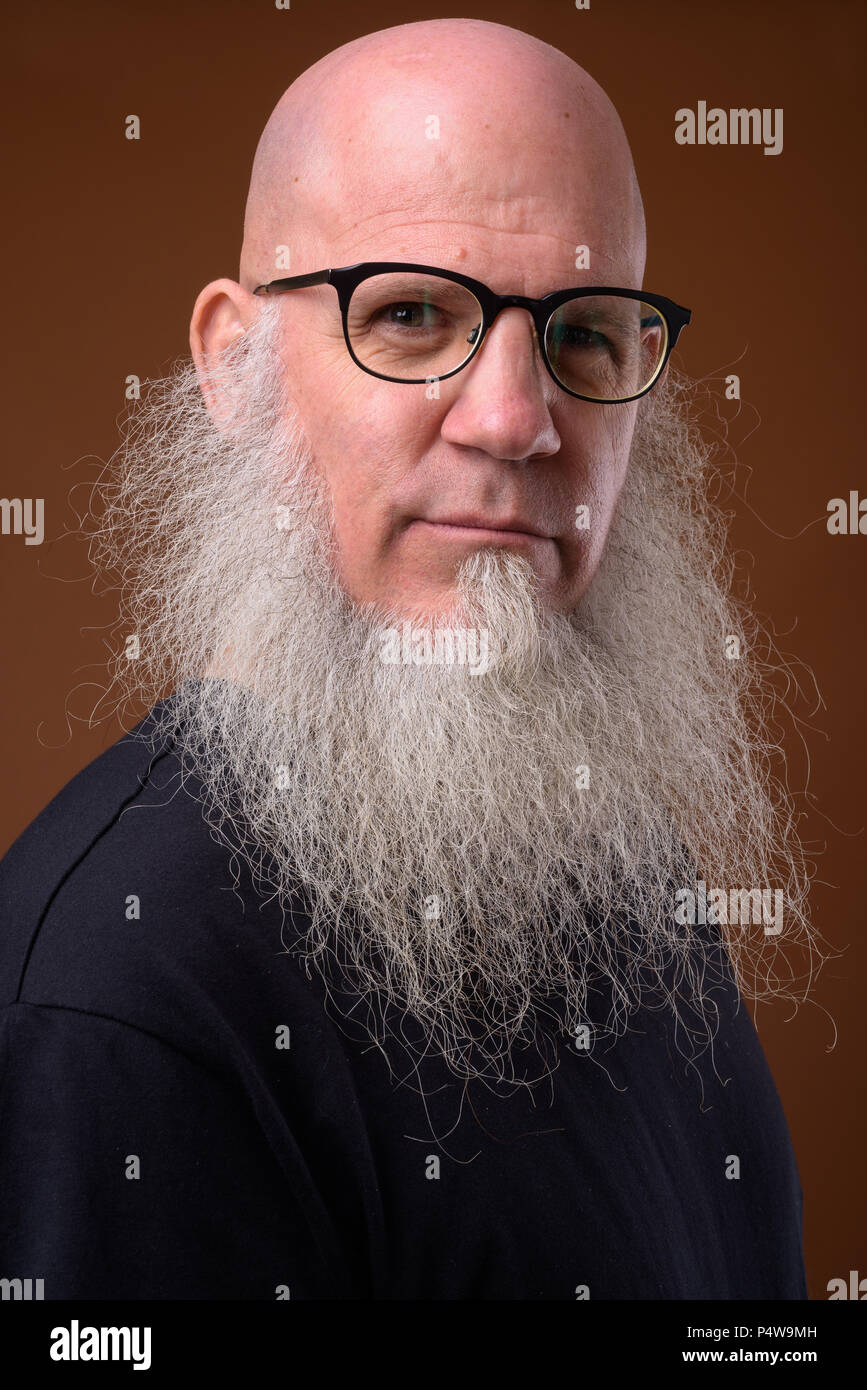 Coppia uomo calvo con una lunga barba grigia contro sfondo marrone Foto Stock