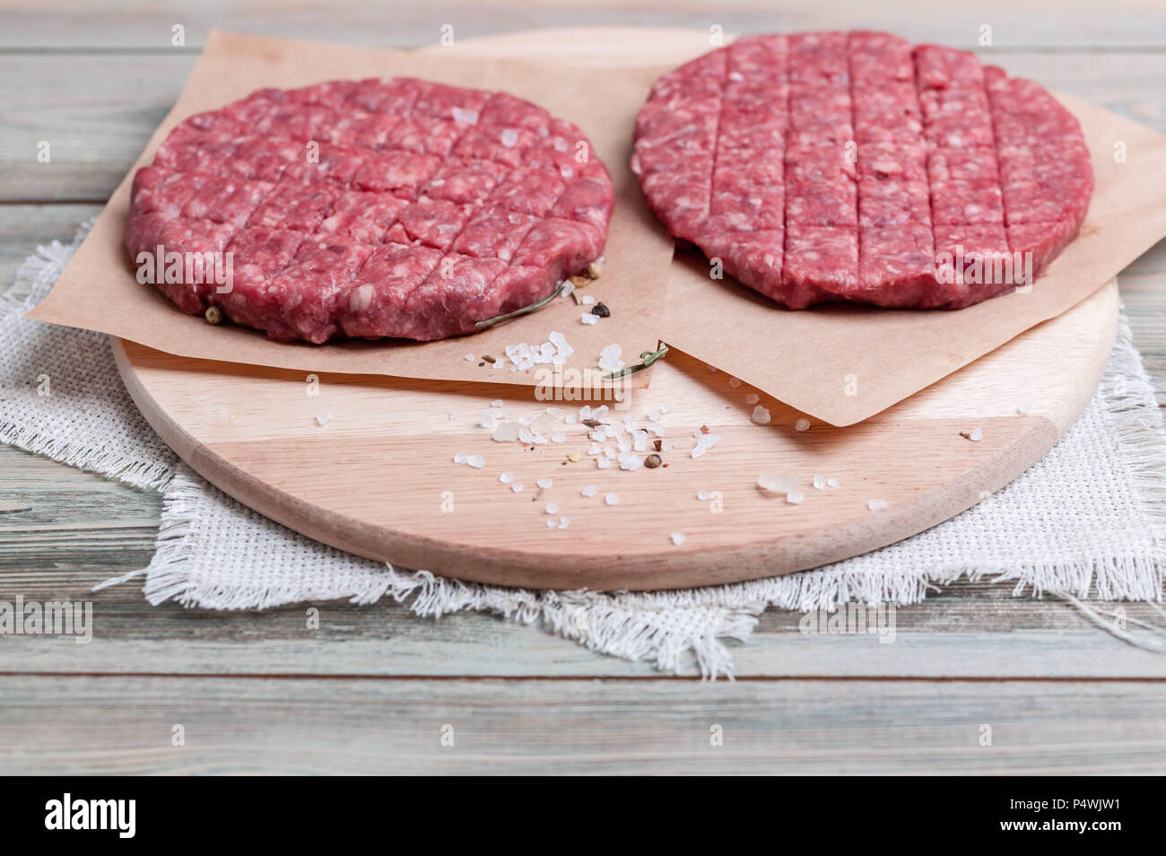 Materie hamburger cotoletta su una tavola di legno con spezie Foto Stock