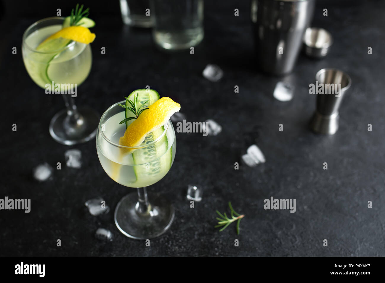Il Gin fizz cocktail con limone, cetriolo, rosmarino e ghiaccio. Il gin tonic o succhiello su sfondo nero, copia dello spazio. Foto Stock