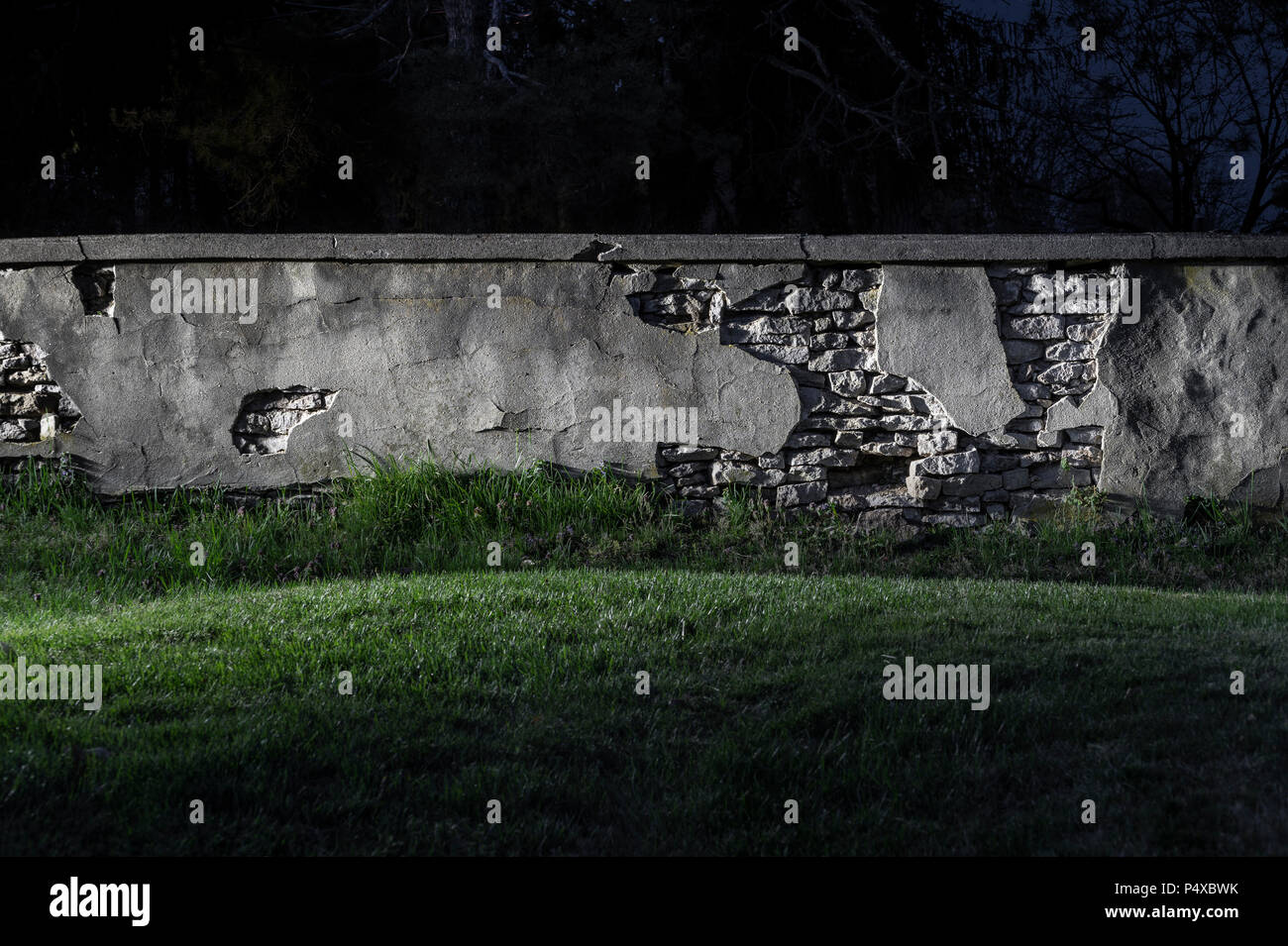 Il vecchio muro di pietra sbriciolamento di notte Foto Stock