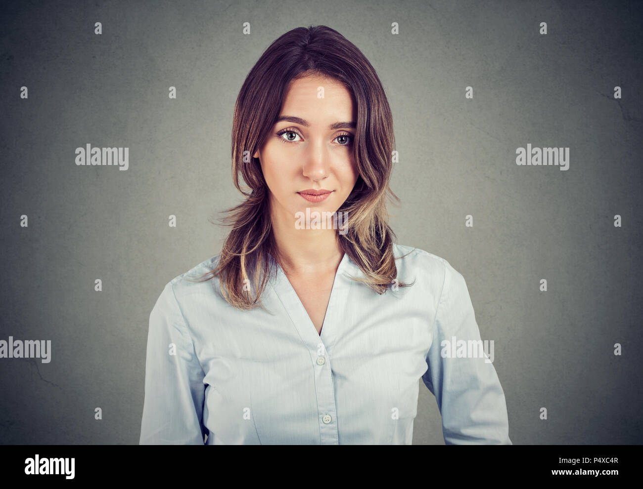 Scettico sospette business giovane donna che guarda la telecamera isolata sul muro grigio sfondo Foto Stock