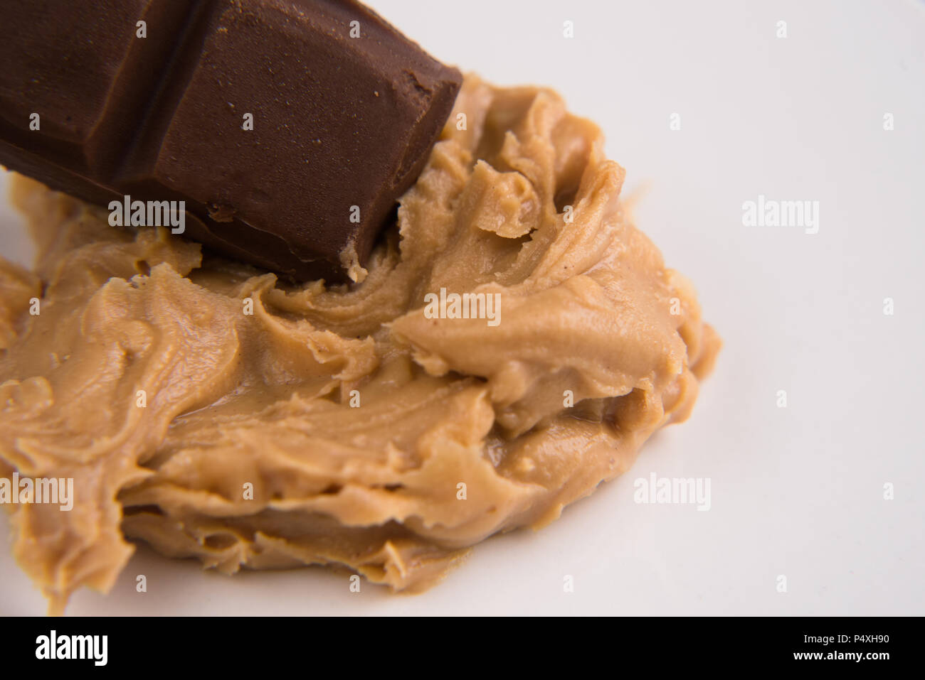 Primo piano di un burro di arachidi e barra di cioccolato su sfondo bianco Foto Stock