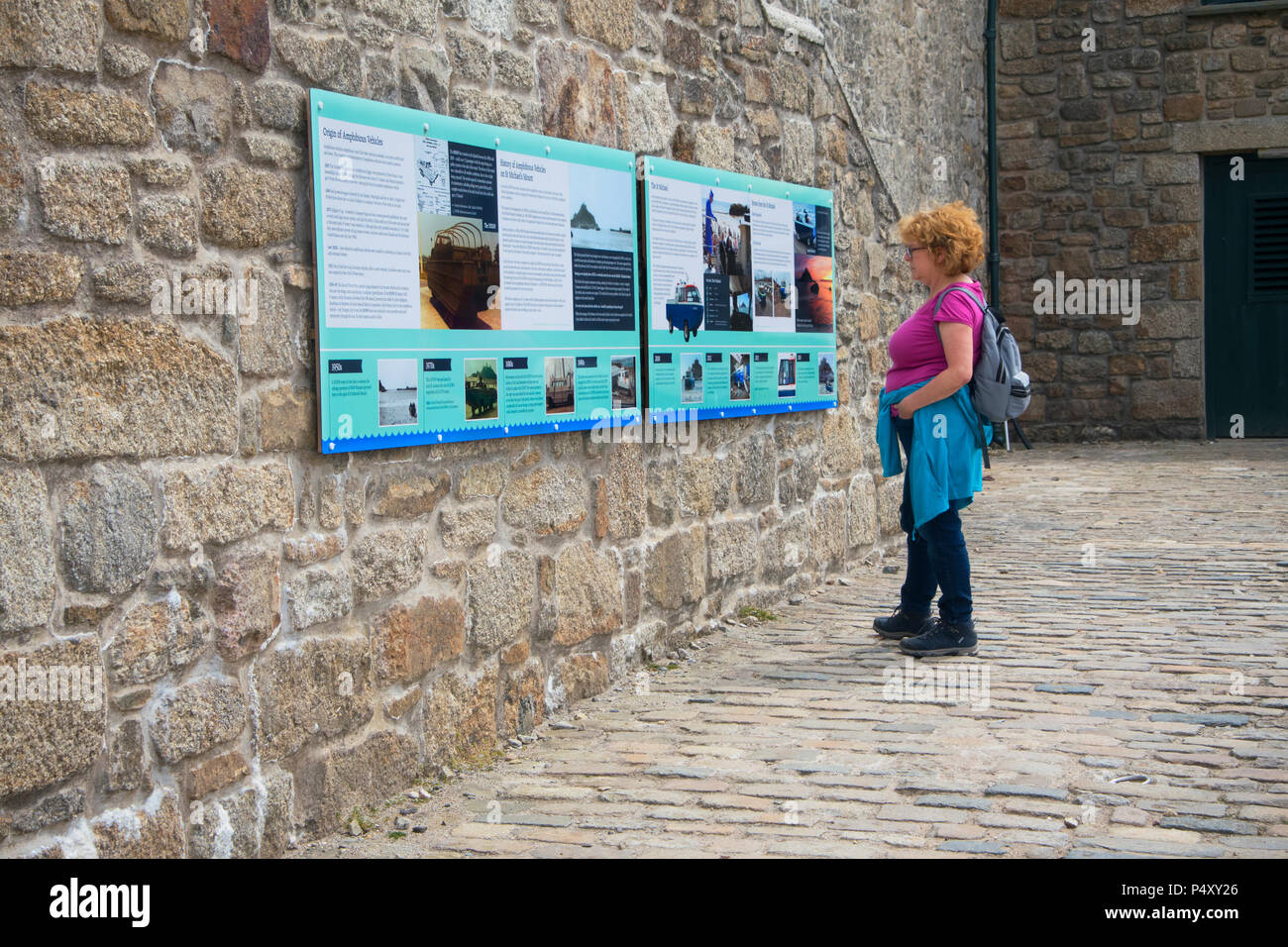 Un turista femminile la lettura dell'Interpretazione presso la parrocchia di San Michele Mount, Cornwall, Regno Unito - Giovanni Gollop Foto Stock