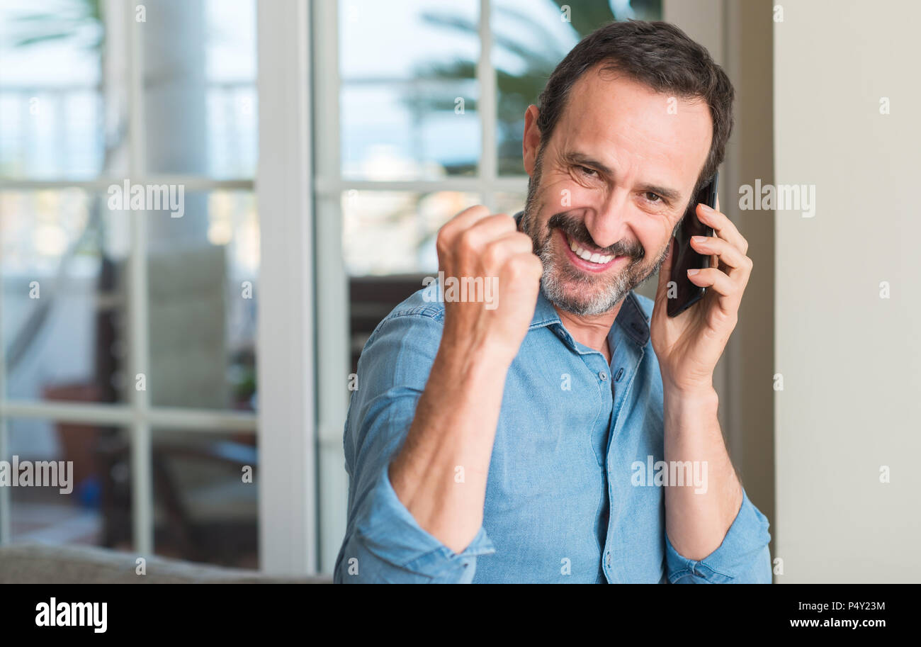 La mezza età uomo utilizza lo smartphone urlando orgoglioso e celebrando la vittoria e il successo molto eccitato, allietarla emozione Foto Stock