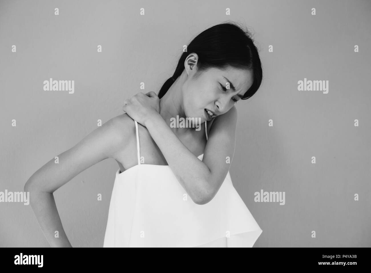 Donna asiatica avente cronici del collo e dolore alla spalla in bianco e nero il tono - sanitari e medici concetto Foto Stock